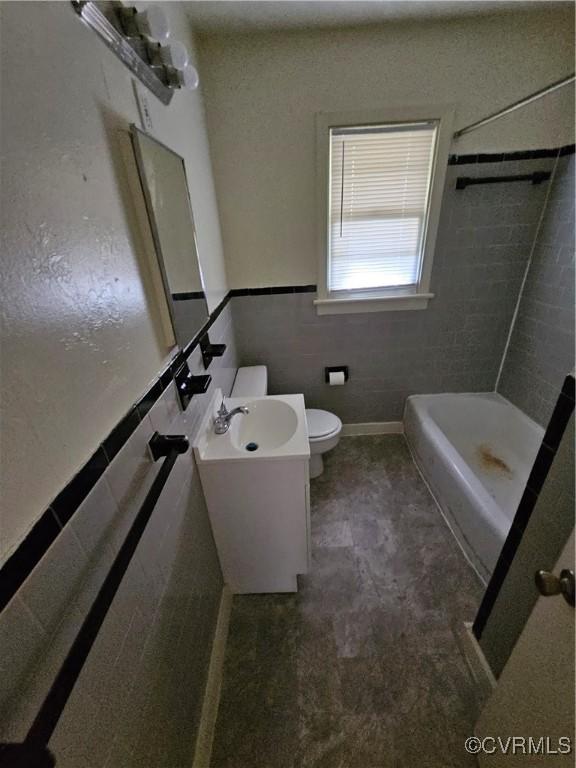 bathroom with vanity, toilet, tile walls, and walk in shower