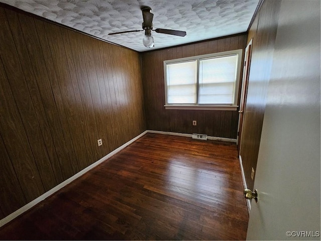 unfurnished room with ornamental molding, dark hardwood / wood-style flooring, wooden walls, and a textured ceiling