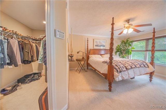 carpeted bedroom with ceiling fan, ornamental molding, and a closet