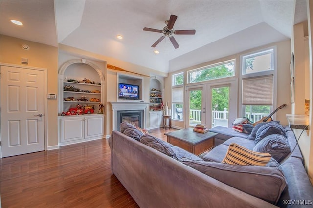 living room with ceiling fan, built in features, dark wood-type flooring, and french doors