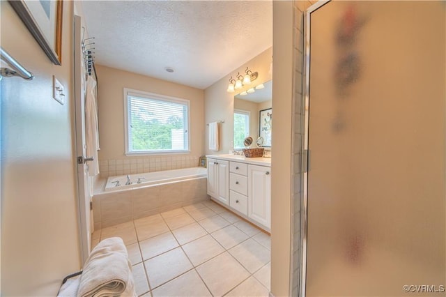 bathroom with tile patterned floors, separate shower and tub, vanity, and a textured ceiling