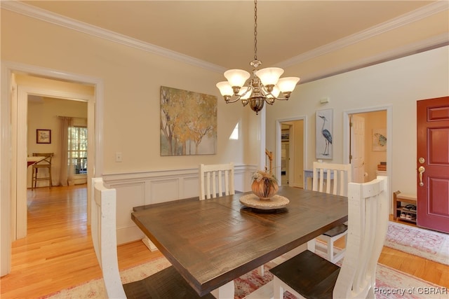 dining room with light wood-type flooring, crown molding, and a notable chandelier