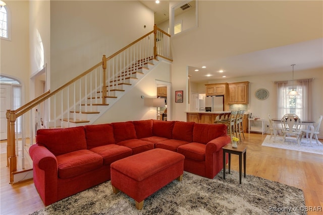 living room featuring a towering ceiling and light hardwood / wood-style floors