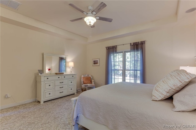 carpeted bedroom featuring ceiling fan and a tray ceiling