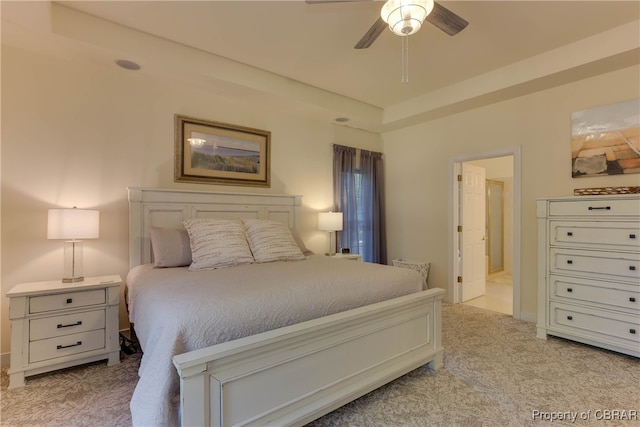 carpeted bedroom featuring a raised ceiling and ceiling fan