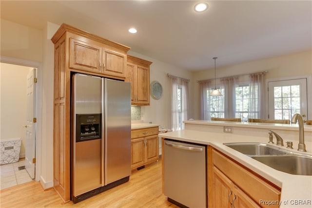 kitchen with sink, light brown cabinets, stainless steel appliances, pendant lighting, and light wood-type flooring