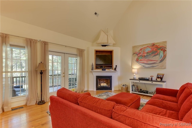 living room with french doors, vaulted ceiling, and light hardwood / wood-style flooring