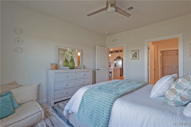 bedroom with ceiling fan, a closet, a spacious closet, and stainless steel refrigerator with ice dispenser