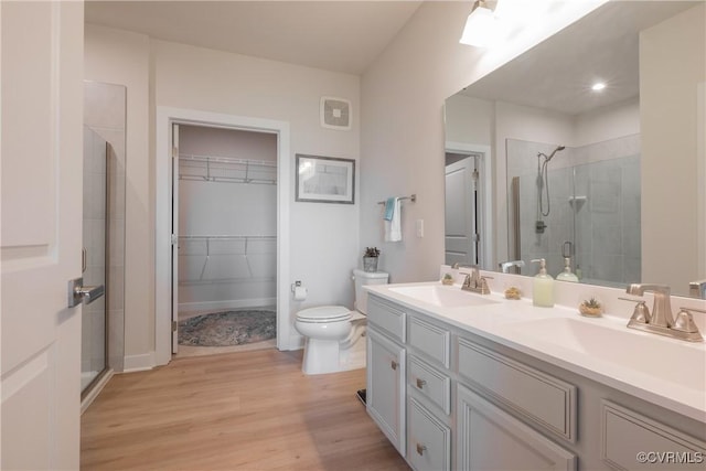 bathroom featuring wood-type flooring, vanity, toilet, and a shower with shower door