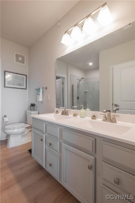 bathroom featuring vanity, toilet, wood-type flooring, and a shower with shower door