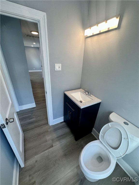 bathroom with toilet, vanity, and hardwood / wood-style flooring