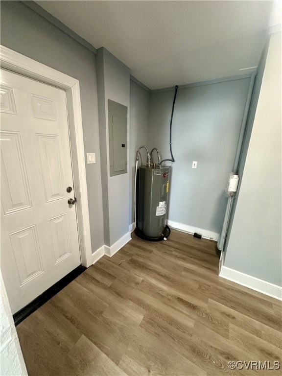 clothes washing area featuring electric panel, electric water heater, and wood-type flooring