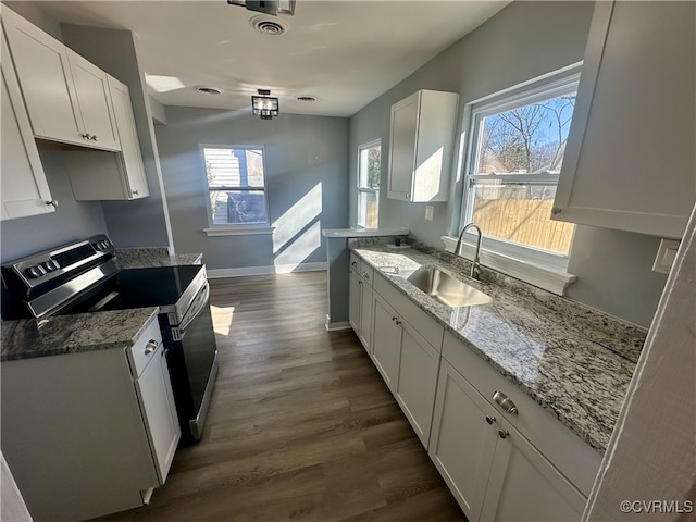 kitchen with electric range, light stone countertops, dark wood-type flooring, sink, and white cabinetry