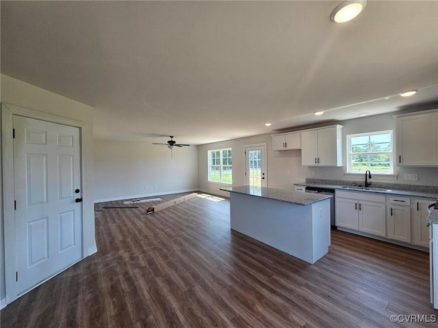 kitchen featuring a center island, dark wood-type flooring, white cabinets, sink, and light stone counters