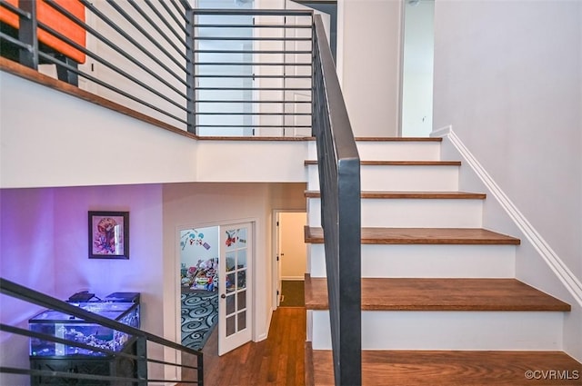 stairs featuring a high ceiling, hardwood / wood-style floors, and french doors