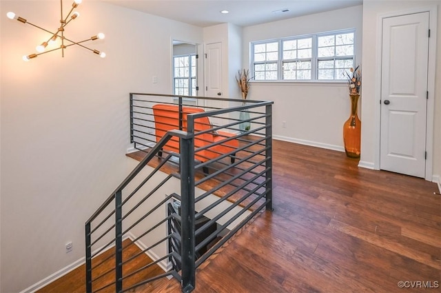 stairs featuring hardwood / wood-style flooring, a healthy amount of sunlight, and an inviting chandelier