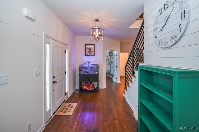 entryway featuring dark wood-type flooring and a chandelier