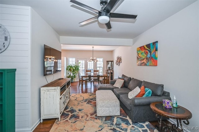 living room with ceiling fan with notable chandelier and dark hardwood / wood-style flooring