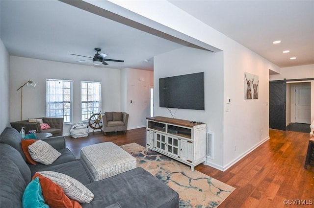 living room featuring dark hardwood / wood-style floors, ceiling fan, and a barn door