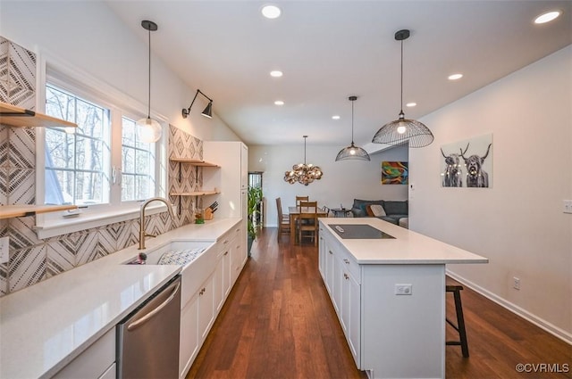 kitchen with hanging light fixtures, stainless steel dishwasher, decorative backsplash, sink, and white cabinets