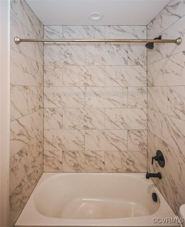 bathroom with tiled shower / bath combo and toilet