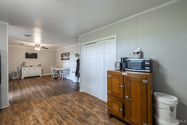 kitchen featuring ceiling fan, dark hardwood / wood-style flooring, ornamental molding, and wooden walls