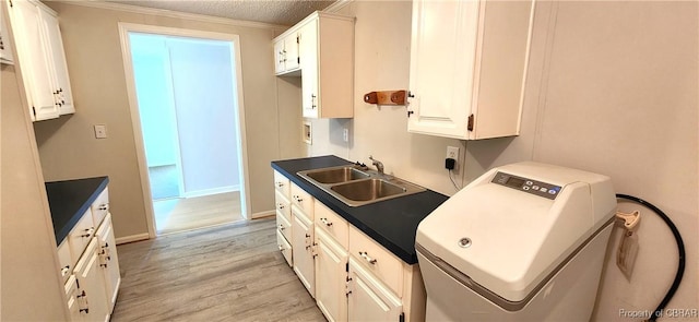 kitchen with sink, light wood-type flooring, a textured ceiling, white cabinets, and ornamental molding