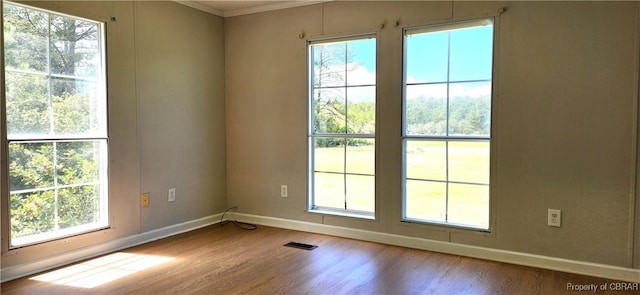 spare room with hardwood / wood-style floors and crown molding