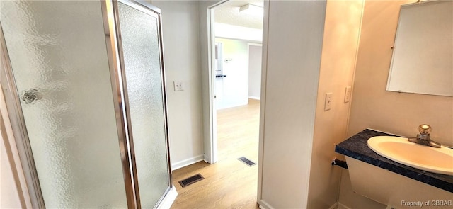 bathroom featuring hardwood / wood-style floors, vanity, and a shower with door