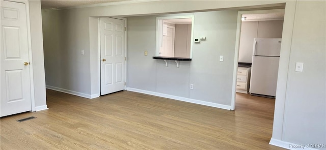 unfurnished bedroom featuring crown molding, light hardwood / wood-style floors, and white refrigerator