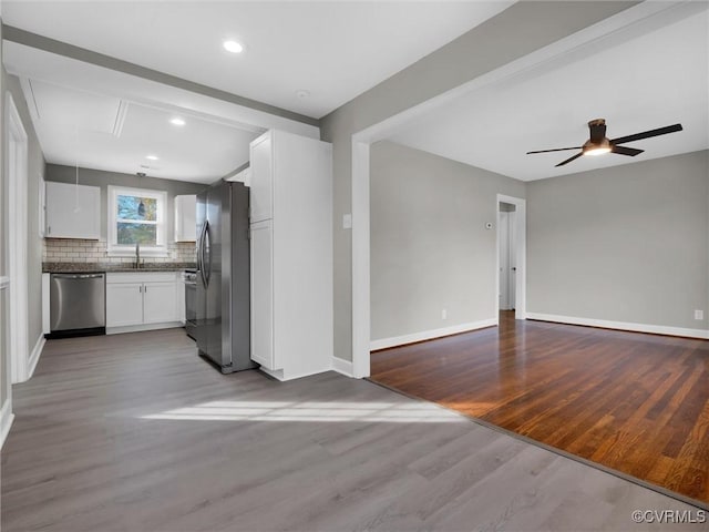 kitchen featuring ceiling fan, stainless steel appliances, hardwood / wood-style floors, decorative backsplash, and white cabinets