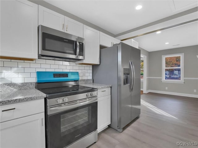 kitchen with white cabinetry, light stone countertops, tasteful backsplash, light hardwood / wood-style flooring, and appliances with stainless steel finishes