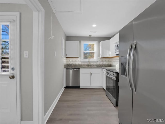 kitchen with decorative backsplash, light wood-type flooring, stainless steel appliances, sink, and white cabinetry