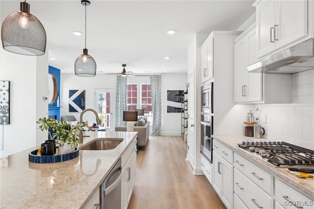 kitchen featuring pendant lighting, white cabinets, sink, light stone counters, and stainless steel appliances