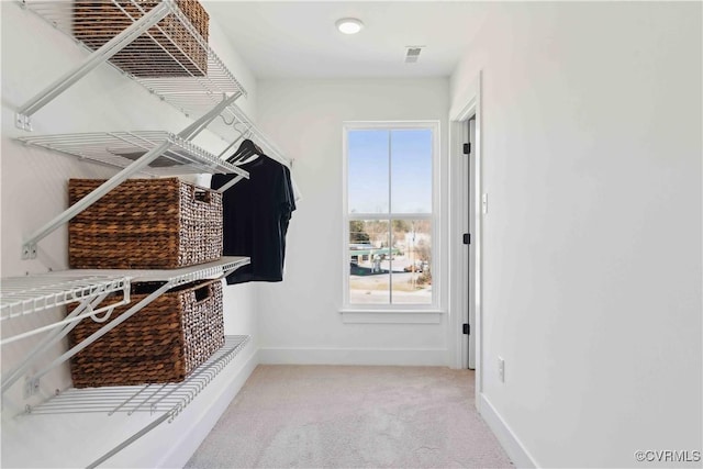 mudroom with baseboards, visible vents, and light colored carpet