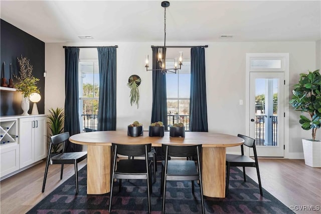 dining room with an inviting chandelier, visible vents, and wood finished floors