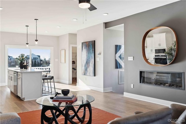 living area with baseboards, visible vents, and light wood-style floors