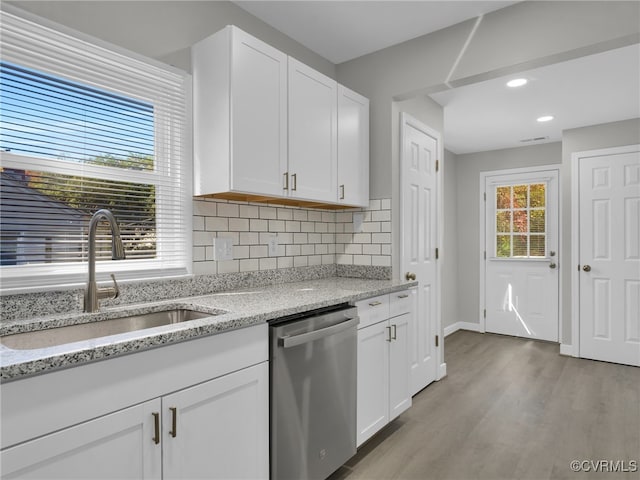 kitchen featuring white cabinetry, sink, backsplash, stainless steel dishwasher, and light stone counters