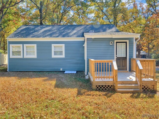 rear view of property with a wooden deck and a yard