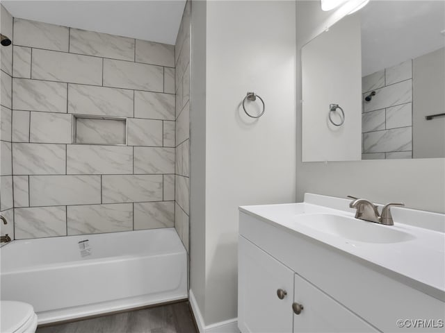 full bathroom with tiled shower / bath, hardwood / wood-style floors, vanity, and toilet