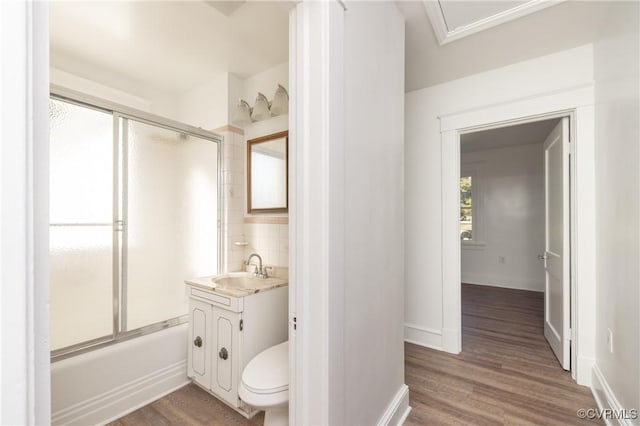 full bathroom featuring vanity, shower / bath combination with glass door, backsplash, toilet, and wood-type flooring