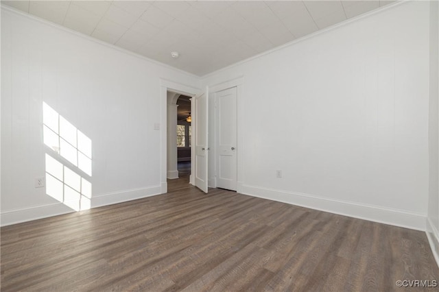 empty room featuring dark hardwood / wood-style flooring and crown molding