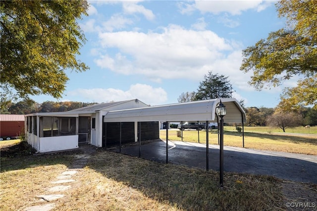 view of front of property with a sunroom, a front yard, and a carport