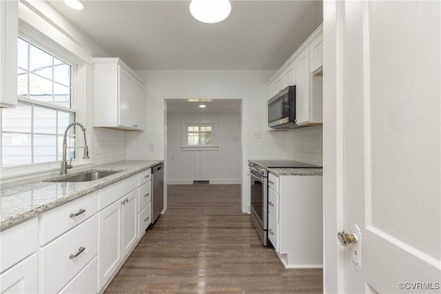 kitchen with white cabinetry, sink, stainless steel appliances, and light stone counters