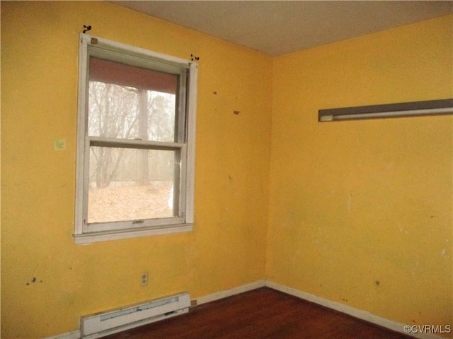 spare room with dark hardwood / wood-style floors and a baseboard heating unit