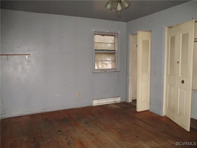 unfurnished bedroom with dark wood-type flooring and a baseboard heating unit