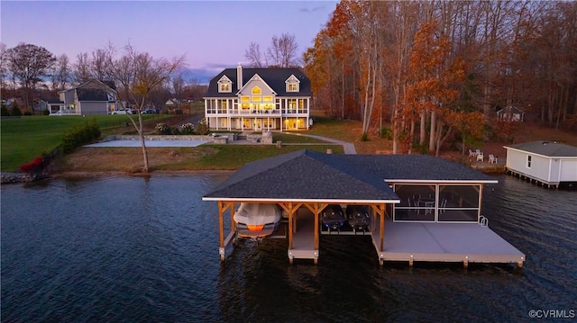 back house at dusk featuring a water view and a yard