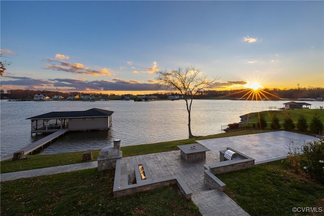 dock area with a lawn, a water view, a patio, and an outdoor fire pit