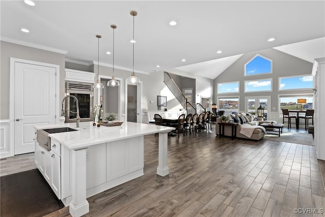 kitchen featuring a center island with sink, decorative light fixtures, white cabinets, and sink