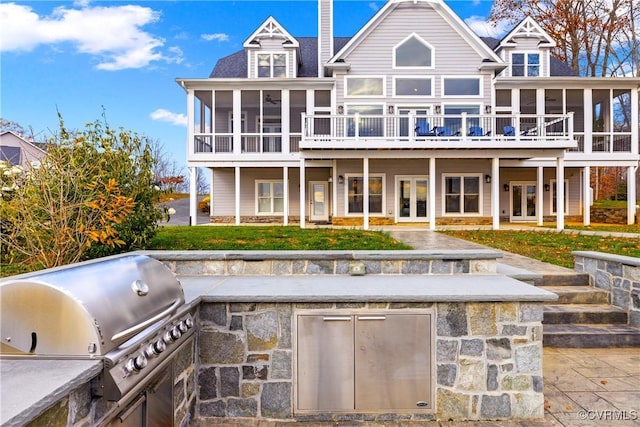 back of property with french doors, a sunroom, a deck, and exterior kitchen